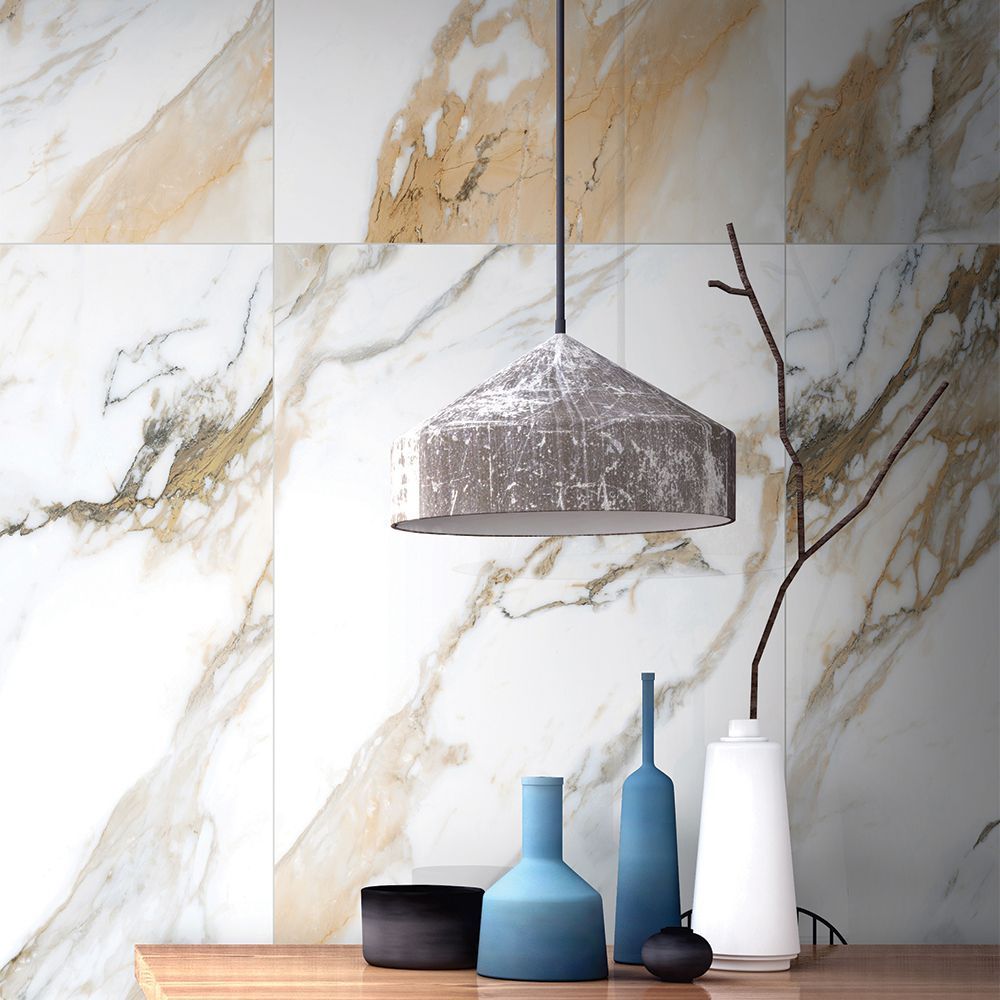 Decorative vases and a lamp on a wooden surface with a marble wall background